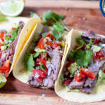 Carne asada tacos med grillet oksekød, guacamole, pico de gallo og frisk koriander på træbræt